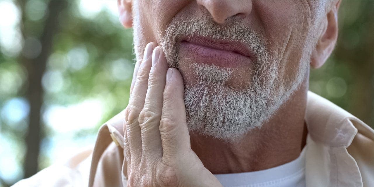 close-up shot of a man holding the side of his mouth