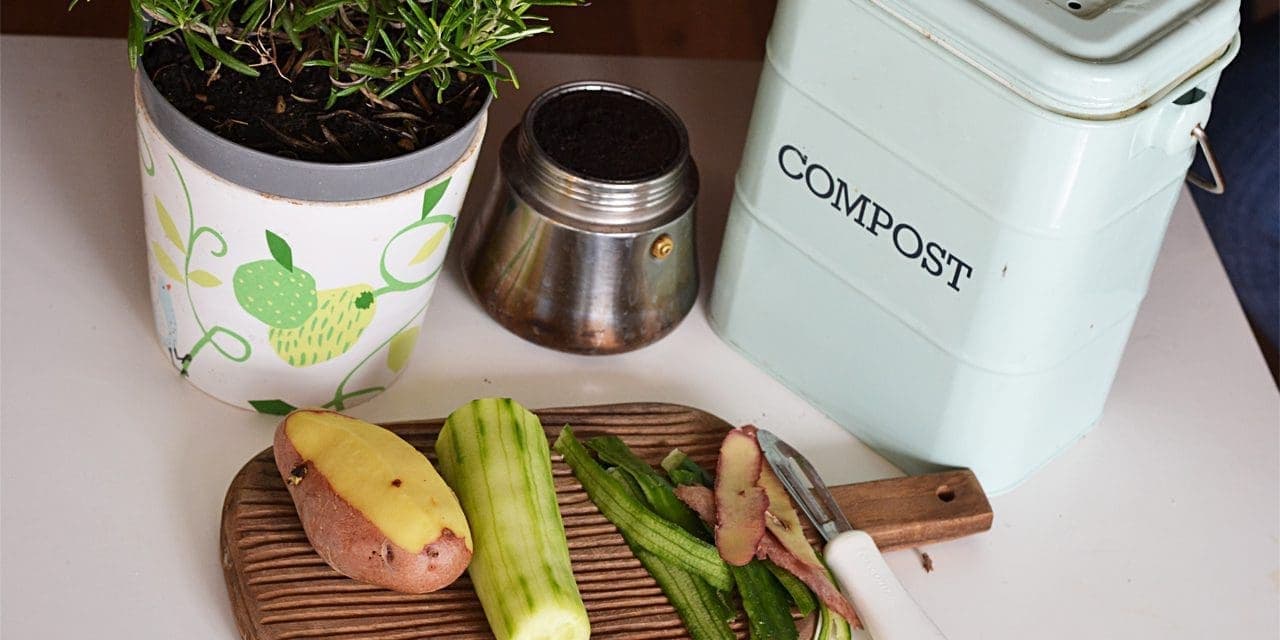 half-peeled vegetables next to a pot and a compost garbage can